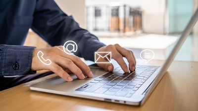 Person clicking on laptop with email and phone icons hovering around